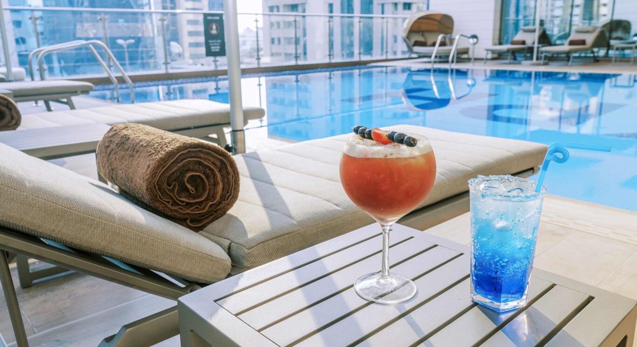 Outdoor pool at Khalidia Palace Hotel Dubai with refreshing beverages and poolside service.